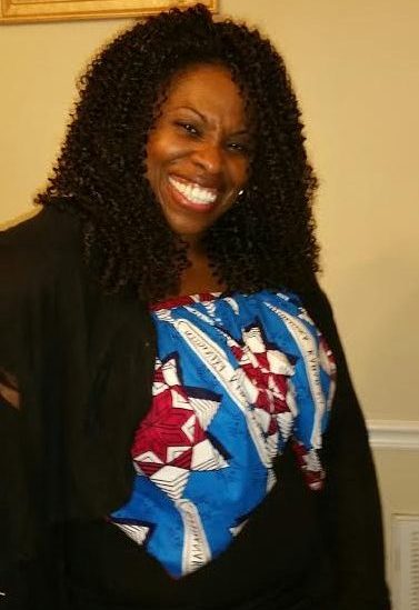 A woman smiling widely while wearing a blue blouse