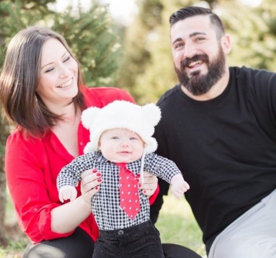 Two parents smiling with their child while sitting in grass