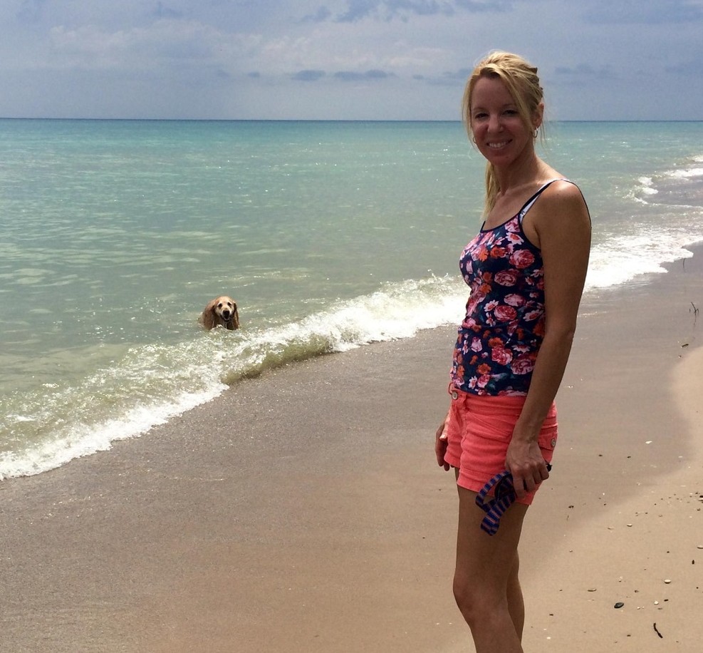 Woman standing on a beach with her dog's leash in hand