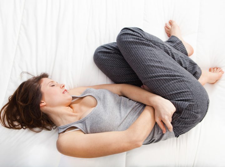 Woman curled into a ball while holding her stomach