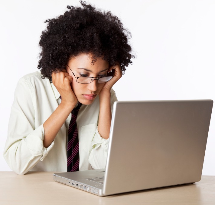 Woman in a dress shirt and tie looking at a laptop