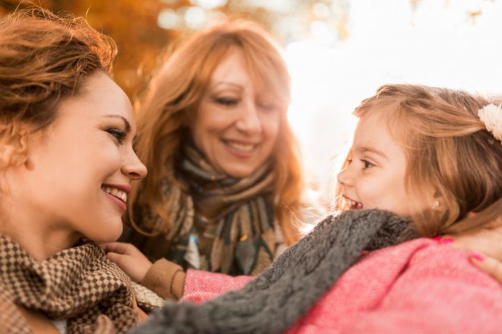 Two women playing with a little girl outside