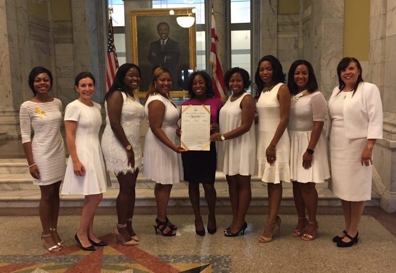 Nine women posing with a document