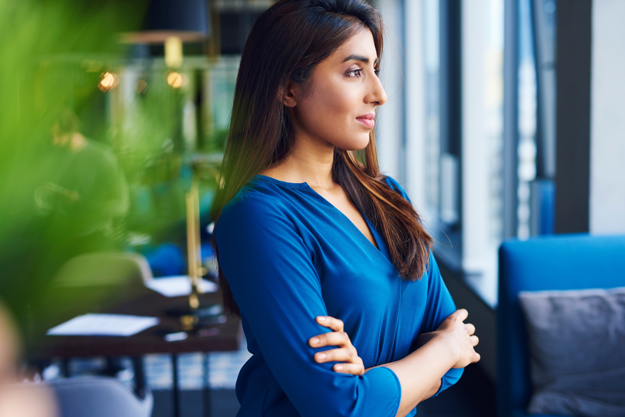 Beautiful Asian woman looking through window in the office