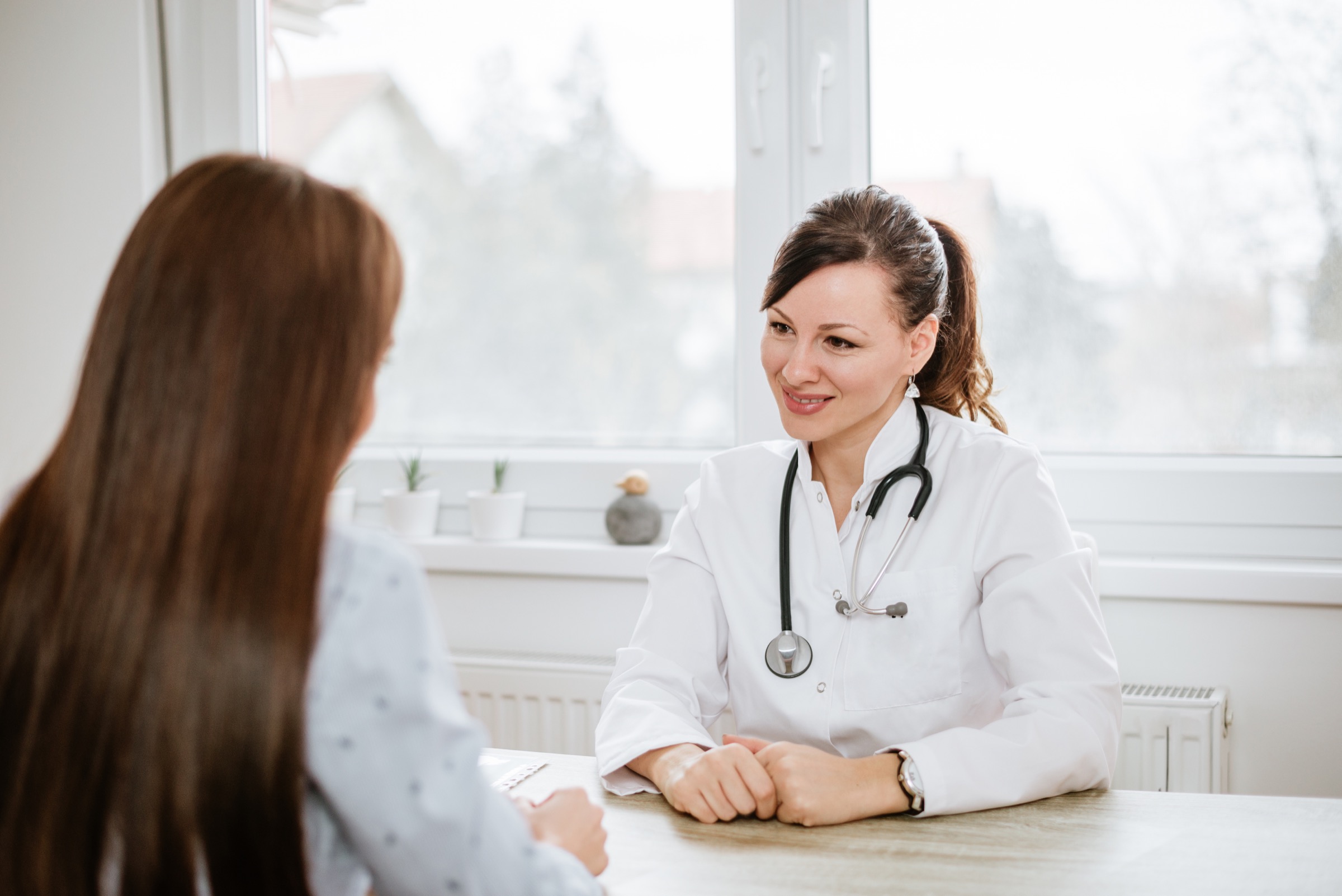 Beautiful female doctor talking with patient in office.