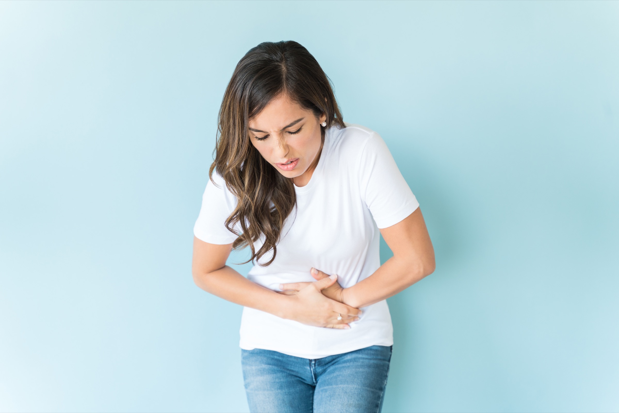 Caucasian woman in pain standing against colored background