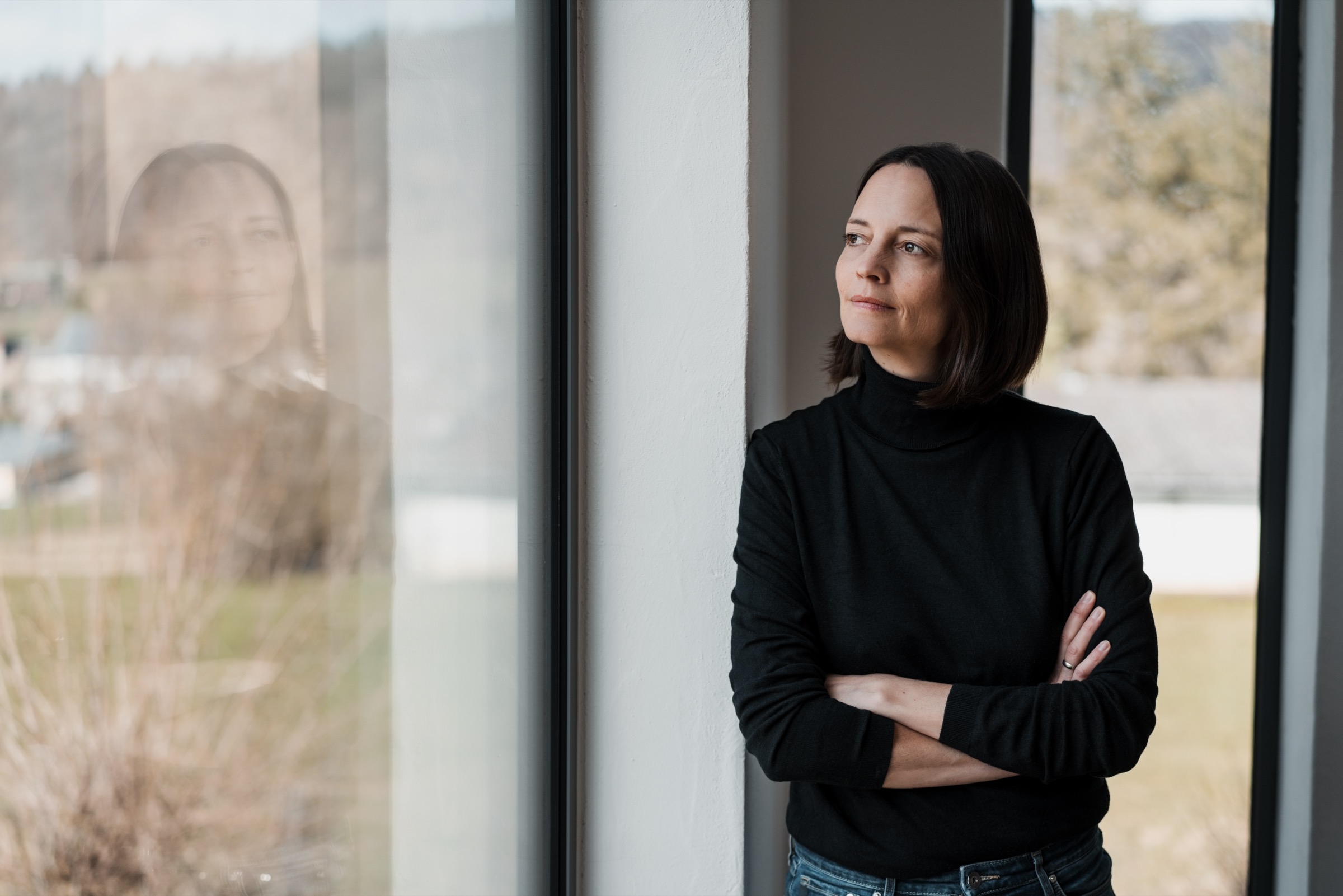 woman leaning against a wall and looking seriously out of the window