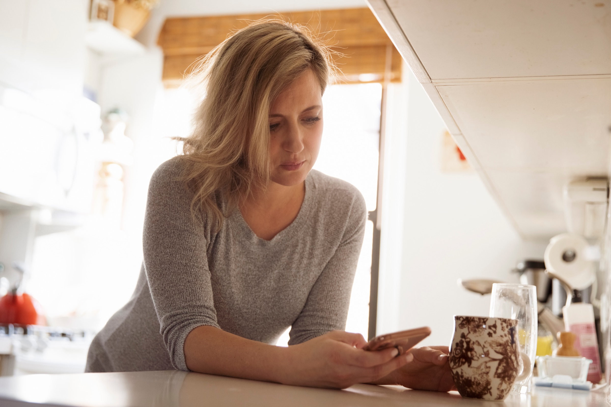 Low angle view of pregnant woman using mobile phone on kitchen counter at home