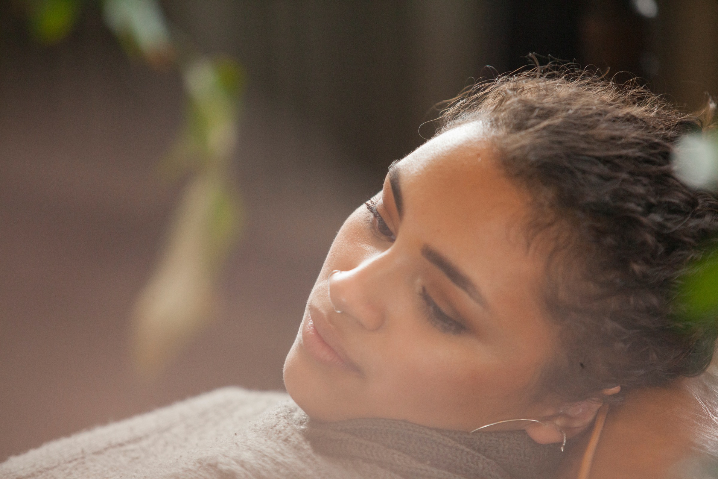 Close-up of thoughtful woman looking away while relaxing on armchair at home